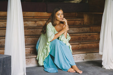 woman sitting on the steps in a dip dye dress with flowy bell sleeves.